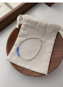 Macro shot of S925 sterling silver beaded bracelet with blue crystals on a beige pouch