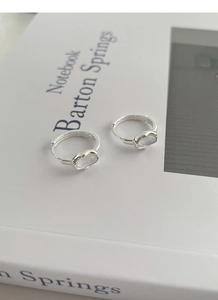 Detail of S925 sterling silver hoop earrings with iridescent moonstones on a white book