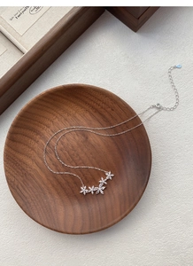 Dettaglio macro della collana di fiori in argento con zirconi su un vassoio di legno