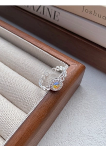 Dettaglio dell'anello in argento 925 con pietra di luna su un supporto per gioielli beige