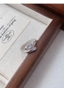 Detail of silver snake-shaped ring with zircon stones on a wooden jewelry tray