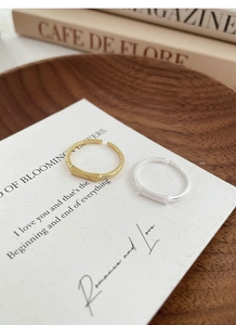 Close-up of minimalist gold and silver brushed metal rings with rectangular bar detail