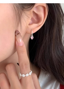 Détail de la boucle d'oreille cœur rose en argent S999 et bague fleur sur modèle