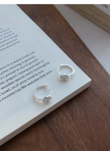 Detail of S925 sterling silver moonstone hoop earrings placed on an open book