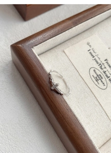 Detailed view of silver cross ring with zircons on a rustic beige fabric background