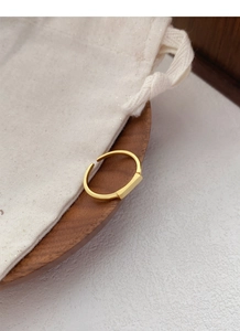 Macro shot of minimalist gold rectangular ring with brushed matte texture on walnut wood