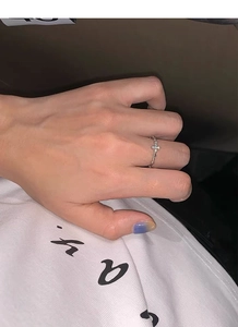 Close-up of minimalist S925 silver cross ring with twist rope band on female finger