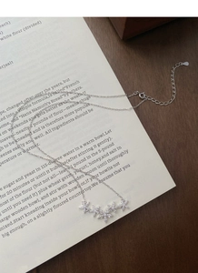 Dettaglio di una delicata collana di fiori in argento con zirconi su un libro