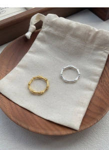 Detailed view of silver and gold bamboo style rings with elegant drawstring jewelry pouch