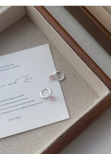 Gros plan de boucles d'oreilles avec pendentif cœur rose sur un plateau à bijoux chic