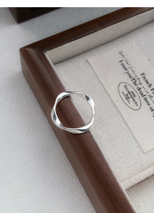 Detail shot of a S999 silver Mobius twist ring resting on a vintage wooden jewelry box
