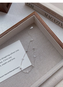 Détail du bracelet S925 en argent perlé avec breloques fleurs sur plateau en bois
