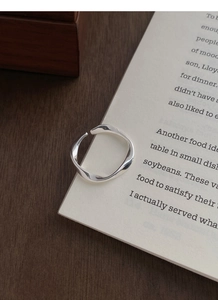 Artistic close-up of S999 silver Mobius twist ring on book pages with elegant shadows