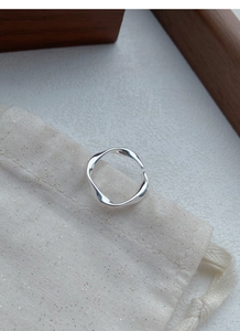 Close-up of S999 sterling silver Mobius ring on a linen jewelry pouch with soft lighting