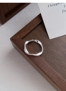 Close-up of a silver Mobius ring on a wooden tray with a minimalist twisted design