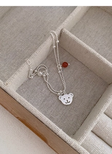 Macro detail of silver double-layer bead bracelet with bear charm and red agate stone