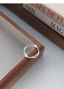Macro shot of S999 silver Mobius ring with wavy lines on a wooden tray with books