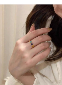 Close-up of a four-leaf clover ring with colorful zircons and golden beaded edges on hand