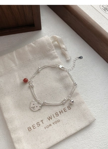 Detail of S925 sterling silver double-layer bracelet with bear charm and red agate bead