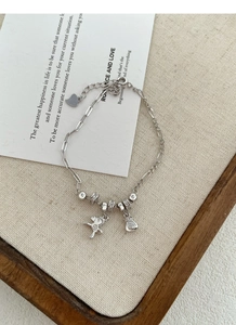 Vue détaillée du bracelet en argent S925 avec breloques poney et sac de monnaie sur plateau