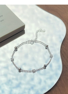 Détails macro du bracelet fleurs en argent sterling S925 sur une surface de miroir