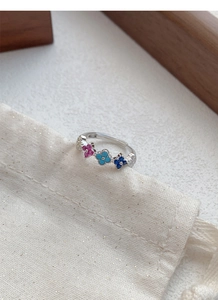 Detail of S925 silver four-leaf flower ring with colorful zircons on a jewelry bag
