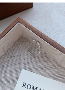 Dettaglio dell'anello a nodo in argento S999 su un vassoio per gioielli in legno sobrio