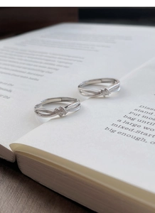 Dettaglio degli anelli a nodo in argento S999 con zirconi su un libro d'epoca