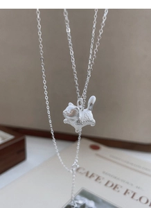 Macro shot of matte S999 silver cat pendant with frosted texture on a wooden jewelry box