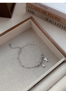 Gros plan d'un bracelet en argent S925 avec breloques lapin et sac à main sur tissu