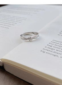 Dettaglio dell'anello a nodo in argento S999 con fascia regolabile su sfondo libro