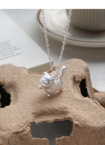 Macro view of textured S999 sterling silver cat pendant on a fine link chain
