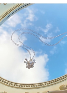 S999 silver cat pendant necklace reflecting blue sky and white clouds on a mirror