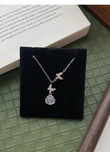 Détail du collier papillon en argent avec pendentif en calcédoine blanche sur support noir