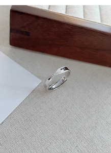 Macro shot of silver twisted knot ring with textured checkerboard facets on wooden jewelry box