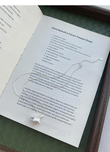 Detailed close-up of S999 silver cat pendant with matte texture on a book page