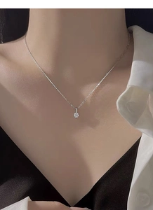 Détail d'un collier en argent avec un pendentif solitaire scintillant porté par un mannequin