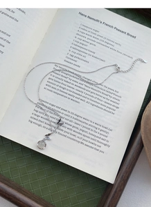 Détail du collier en argent S925 avec papillon et calcédoine blanche sur un livre ouvert