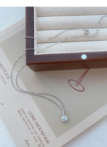 Vue détaillée du collier en argent S999 avec un seul zircon brillant sur une boîte en bois