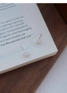 Gros plan artistique de boucles d'oreilles fleurs en argent S999 sur une page de livre