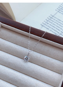 Détail d'un pendentif diamant unique sur chaîne en argent S999 posé sur un support velours
