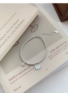 Détail du bracelet en argent S999 avec breloque étoile rose et pendentif papillon blanc