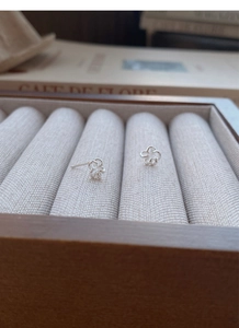 Vue macro des boucles d'oreilles fleurs ajourées en argent S999 sur une boîte en bois