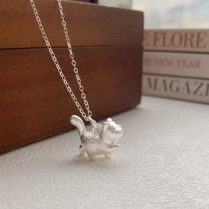 Minimalist S999 sterling silver cat necklace with matte texture on a decorative background