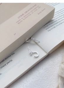 S999 Silber C-Creolen mit Zirkonia, die bei weichem Licht auf einem Buch liegen