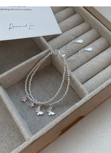 Détail du bracelet double couche en argent S999 avec breloques étoile rose et papillon blanc