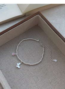Détail du bracelet en argent S999 avec breloques étoile rose et papillon blanc