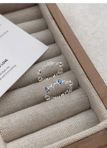 Detail of S925 silver rings with blue and white zircons in a wooden jewelry box