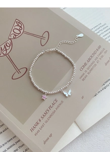 Gros plan d'un bracelet en argent S925 avec breloques étoile rose et papillon blanc