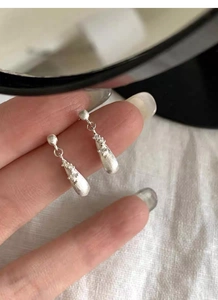 Close-up of S925 sterling silver teardrop earrings with brushed finish and zircon detail